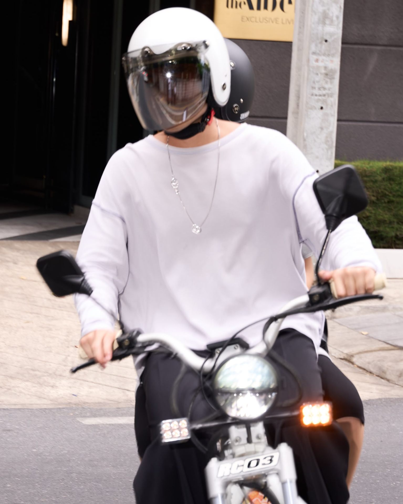 Rider on motorbike wearing HELMYY pearl white helmet with clear shield